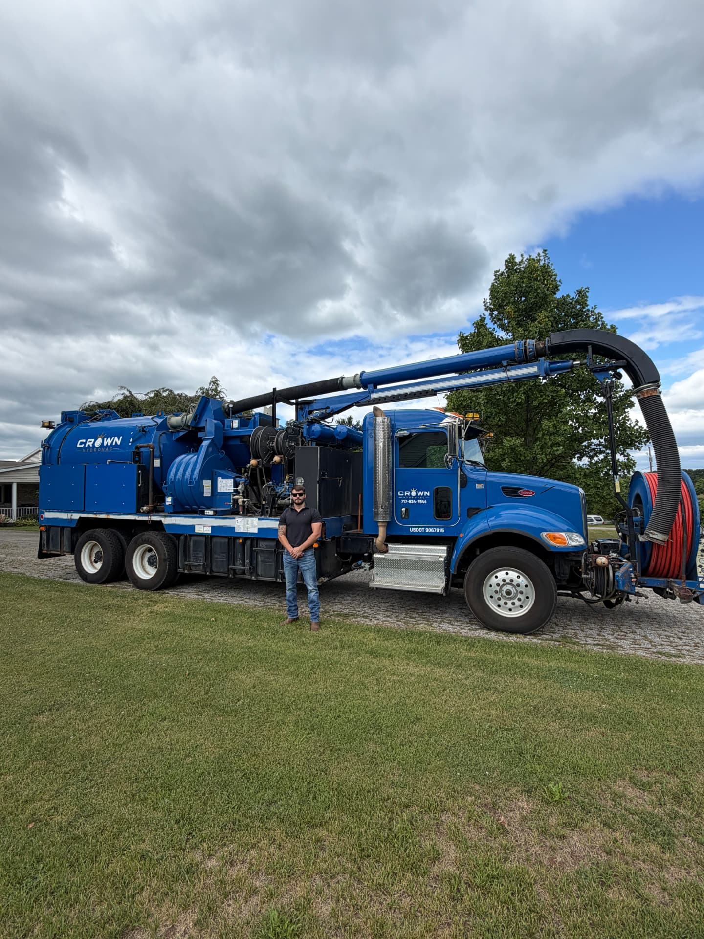 Crown Hydrovac crew member standing beside the blue vacuum truck